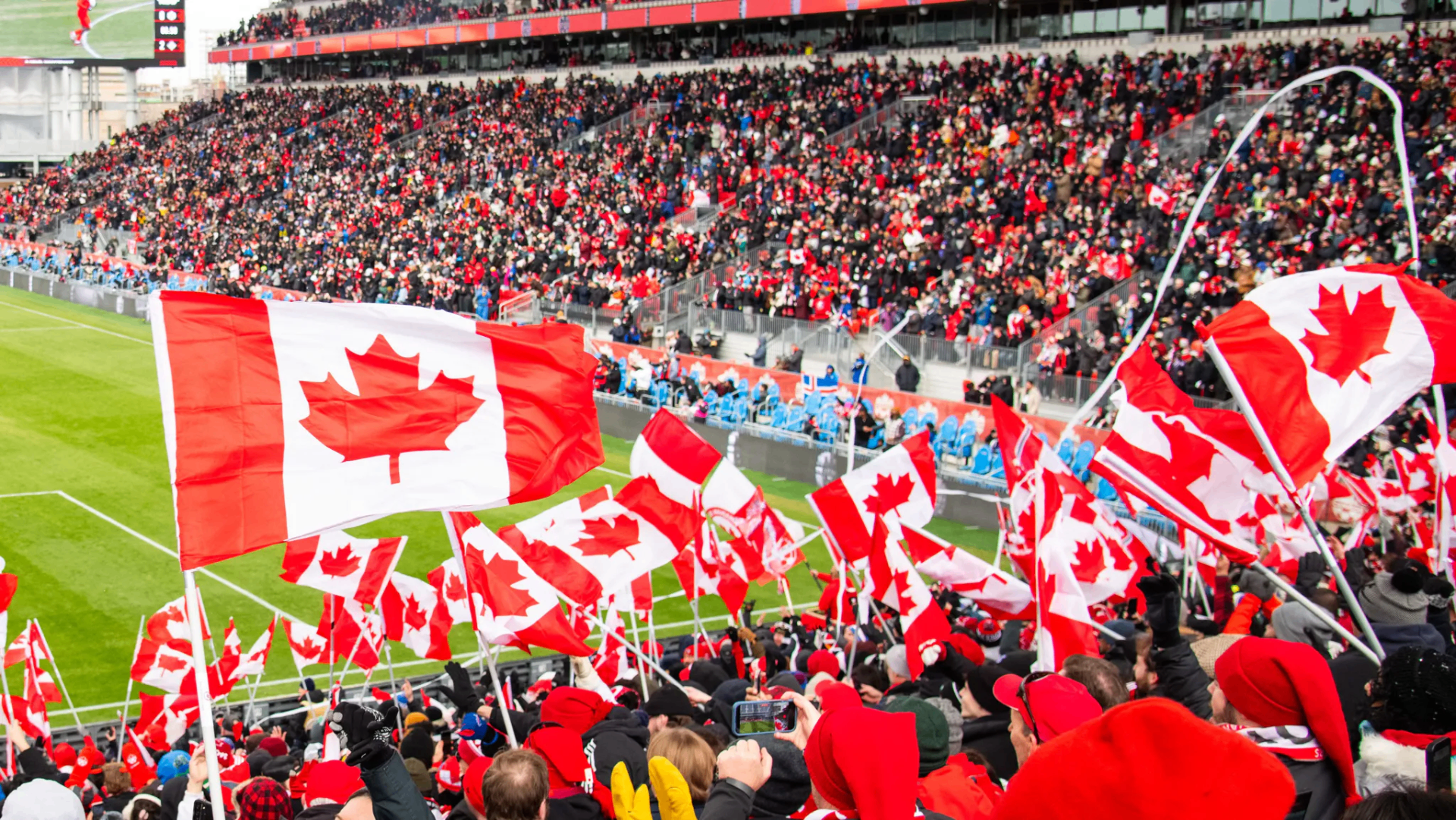 Canadian soccer fans waving flags in a packed stadium